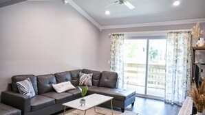Una sala moderna con un sofá de cuero, una mesa de centro blanca y un ventilador de techo.