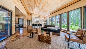 A spacious living area with a wooden ceiling, large windows, a sofa, and a coffee table.
