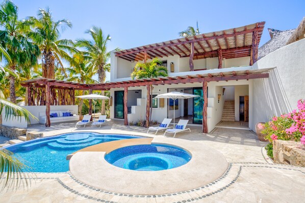A modern resort with a swimming pool, lounge chairs, and a covered patio area. - Lower Palmilla: Oceanfront room with pivate pool and jacuzzi (La Paz)