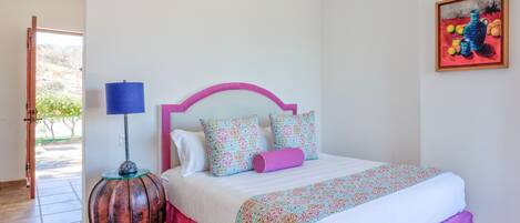 A bedroom with a bed, a lamp, and a painting on the wall.