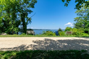 A gravel path leading to a bench and a chair by a lake, surrounded by trees. - Waterfront Sunsets, Fishing, Boating, and Crabs! Paxs River, Budds Creek MIR. (Maddox)