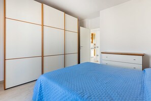 A bedroom with a bed, a wardrobe, and a dresser.