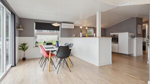 A modern kitchen with white cabinetry, a central island, and a dining area with a table and chairs. - Amazing home in Børkop with WiFi (Børkop)