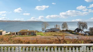 A coastal property with a view of the sea, featuring modern and traditional buildings, a wooden fence, and a grassy foreground. - Amazing home in Børkop with WiFi (Børkop)