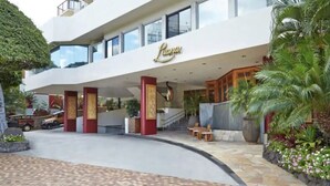 A modern hotel with a prominent entrance, a covered outdoor area with seating, and lush landscaping. - Amazing view in the beautiful Luana Waikiki! (Honolulu)