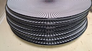 Une pile d’assiettes rayées en noir et blanc posée sur une surface blanche.