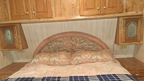 Une chambre à coucher avec un lit, des armoires en bois et une fenêtre ornée d’un panneau de verre décoratif.