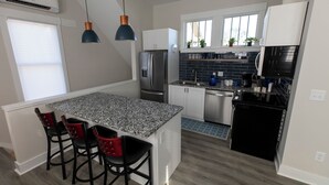 A modern kitchen with granite countertops, stainless steel appliances, and a small island with bar stools.