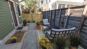 A wooden deck with a seating area, potted plants, and a wooden fence.