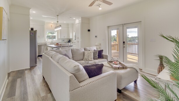 A modern living room with a beige sofa, a coffee table, and a dining area with a chandelier. - Waterfront Pass Christian Paradise: 1 Mi to Beach (Pass Christian)