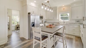 A kitchen with white cabinets, a wooden dining table, and a stainless steel refrigerator. - Waterfront Pass Christian Paradise: 1 Mi to Beach (Pass Christian)