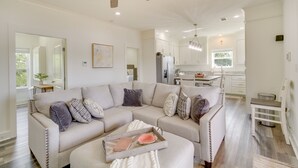 A spacious living room with a large beige sectional sofa, a ceiling fan, and a kitchen area in the background. - Waterfront Pass Christian Paradise: 1 Mi to Beach (Pass Christian)