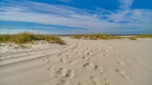 A sandy beach with footprints and grass. - Waterfront Pass Christian Paradise: 1 Mi to Beach (Pass Christian)