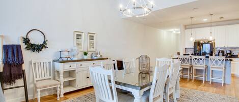 A spacious kitchen with white cabinetry, a central island, and a chandelier.