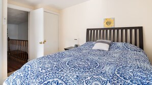 A bedroom with a bed, a nightstand, a wall clock, and a door leading to a staircase. - Cozy 2nd Floor3 bedroom unit with off street parking (Sinking Spring)
