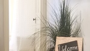 A hallway with a wooden door, a welcome sign, and a potted plant. - Cozy 2nd Floor3 bedroom unit with off street parking (Sinking Spring)