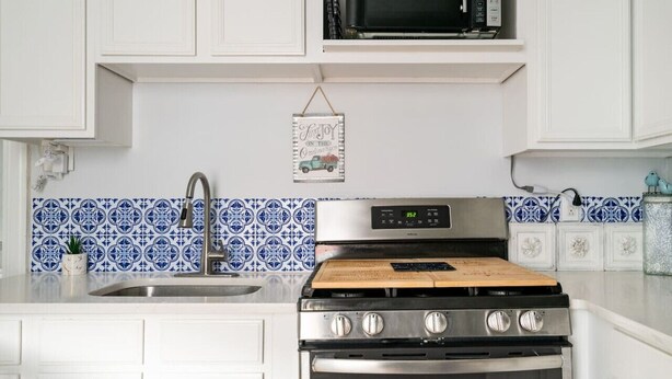 A kitchen with white cabinets, a stainless steel stove, a microwave, and blue patterned backsplash tiles. - Cozy 2nd Floor3 bedroom unit with off street parking (Sinking Spring)