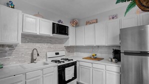 Una cucina moderna con mobili bianchi, un frigorifero in acciaio inossidabile, un fornello a gas e un forno a microonde.