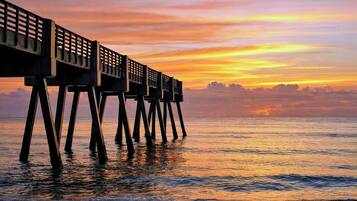 Un muelle que se adentra en el agua, con un atardecer de fondo.