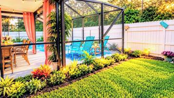 Un patio couvert avec une piscine, des sièges d’extérieur et une pelouse bien entretenue.
