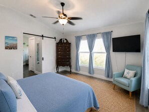 A bedroom with a bed, a dresser, a television, and a chair.