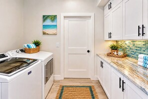 Un cuarto de lavado con lavadora, secadora y una puerta que da a otra habitación.