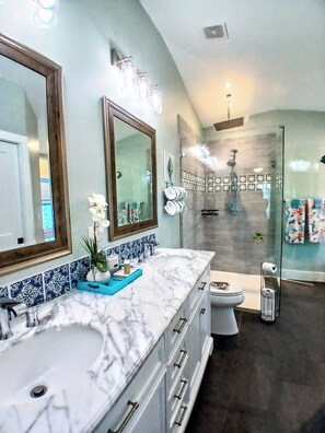 Un baño moderno con un espejo grande, un lavamanos de mármol y una cabina de ducha de vidrio.