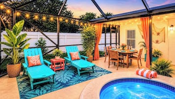 Un patio al aire libre con piscina, zona de estar y luces colgantes.