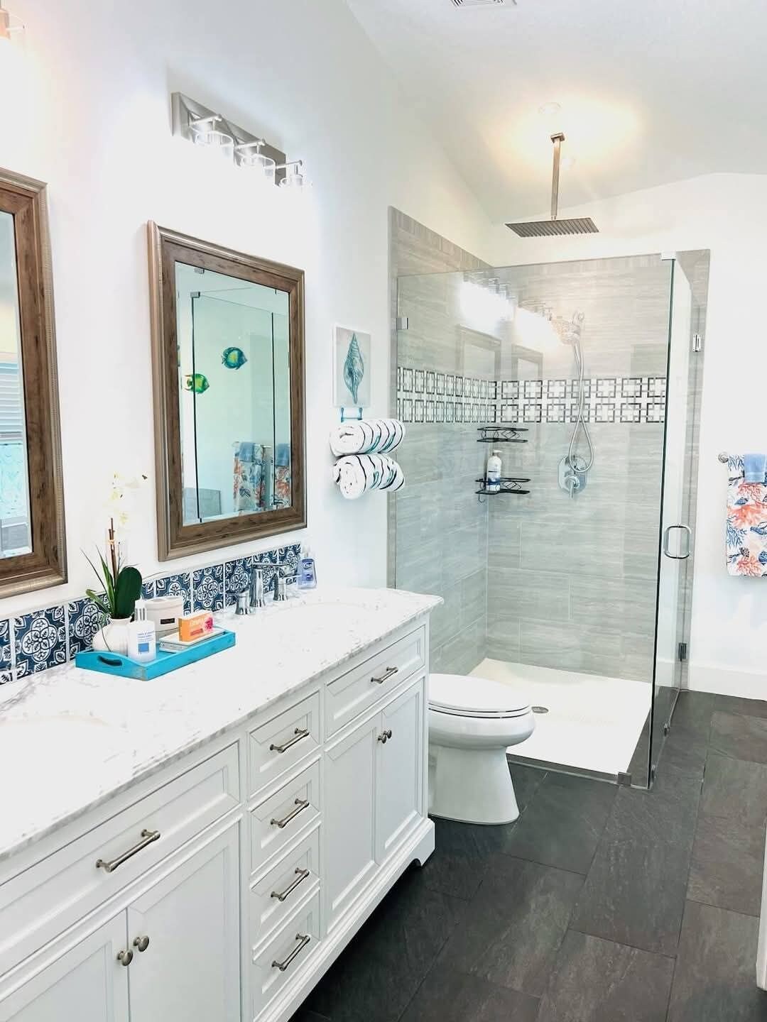 Un baño moderno con cabina de ducha de vidrio, un inodoro blanco y un tocador con espejo y toallero.