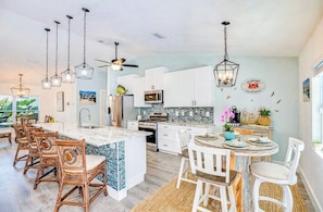Una cocina moderna con una isla central, armarios blancos e iluminación colgante.