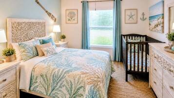 A bedroom with a bed, nightstands, a crib, a dresser, and decorative wall art.