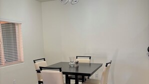 A dining area with a rectangular table, four chairs, a chandelier, and a window with blinds. - 3-bedroom condo in pleasant Mesquite with AC, WiFi. Enjoy your stay (Mesquite)