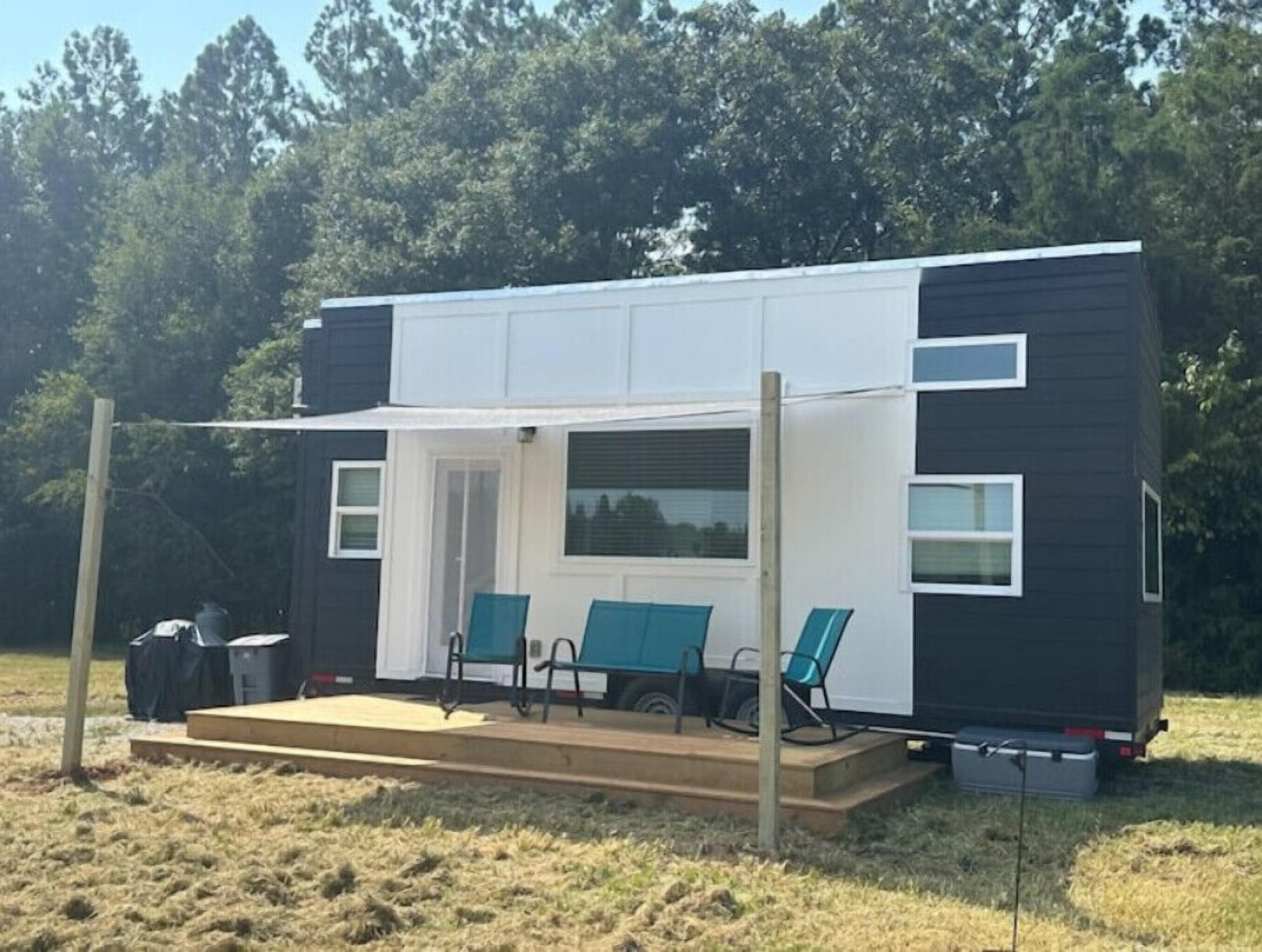 Ein kleines, zweistöckiges Mobilheim mit Veranda und Sitzbereich im Freien.