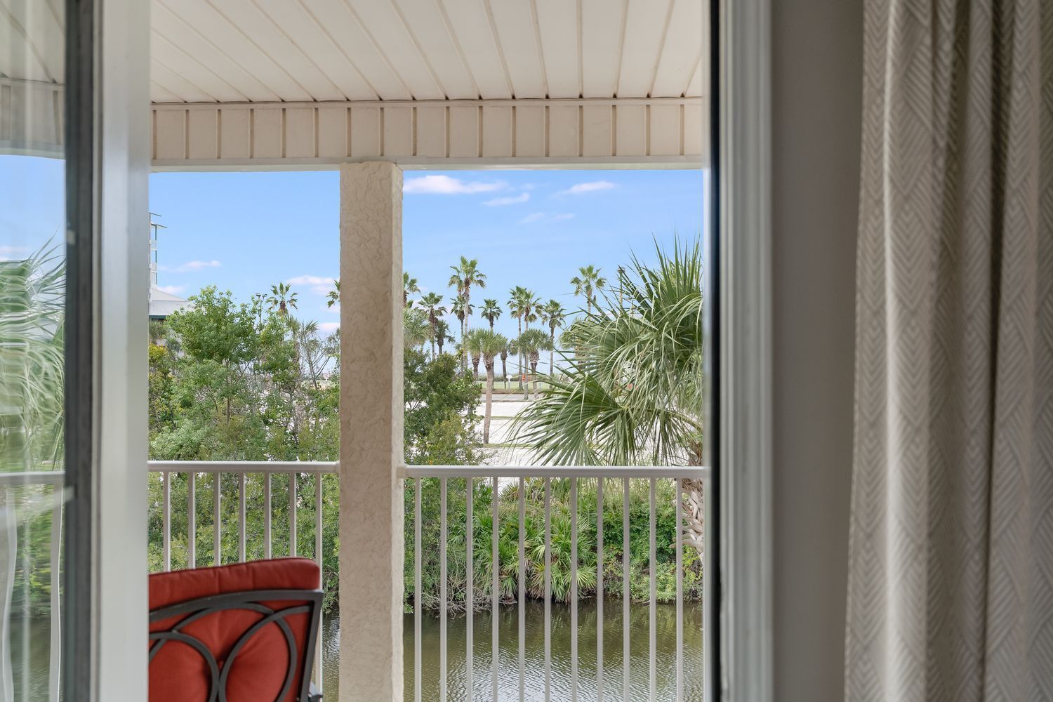 A balcony with a view of palm trees and a water body.