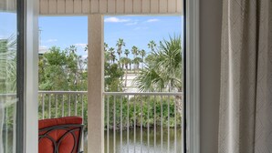 A balcony with a view of palm trees and a water body.