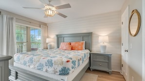 A bedroom with a bed, nightstands, a ceiling fan, and a window with curtains.