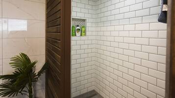 Een badkamer met witte betegeling, een kamerplant en een douchehoek.