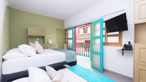 Un dormitorio con dos camas, un televisor montado en la pared y un balcón con barandillas coloridas.