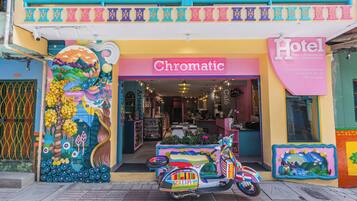 Una entrada de hotel colorida con un mural vibrante, una moto y un letrero que dice 'Chromatic Hotel'.