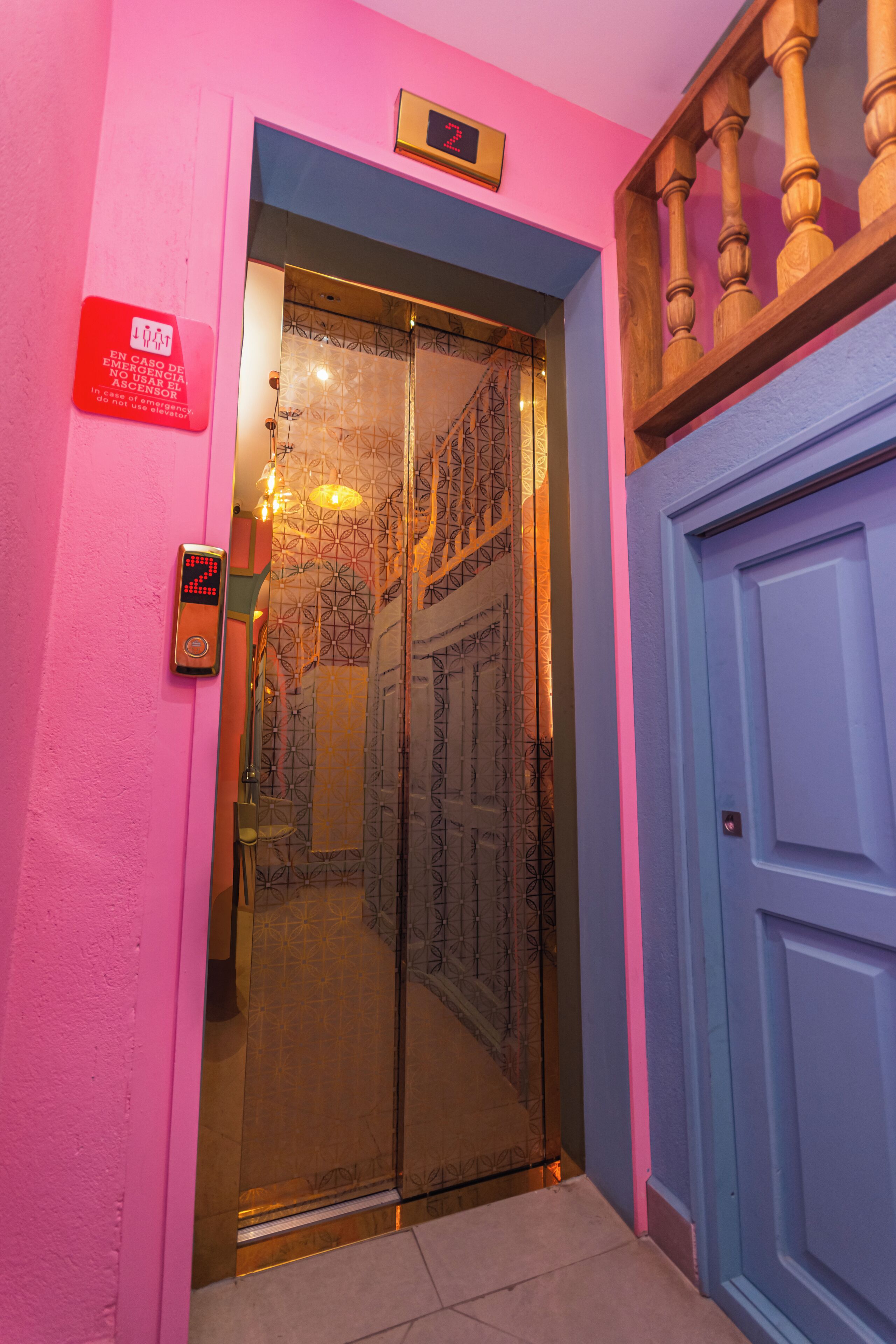 A hotel entrance with a digital clock, a sign, and a blue door.