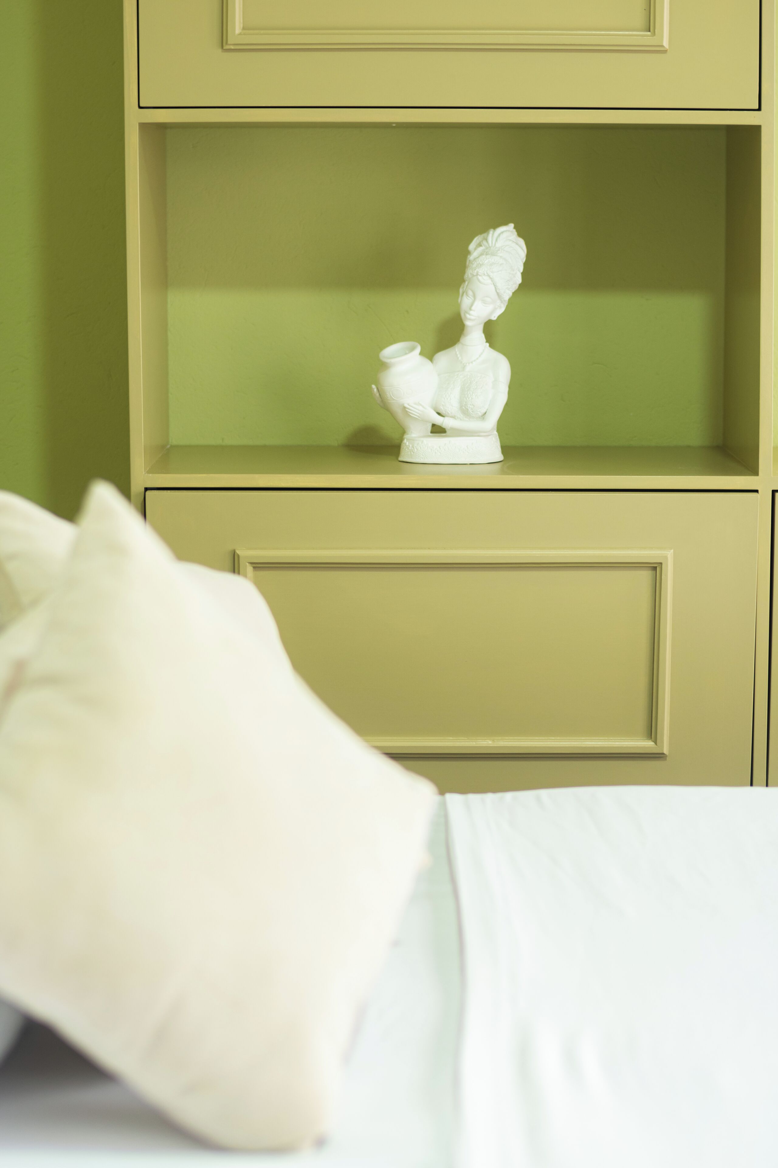 A bed with white bedding and a cream-colored pillow.