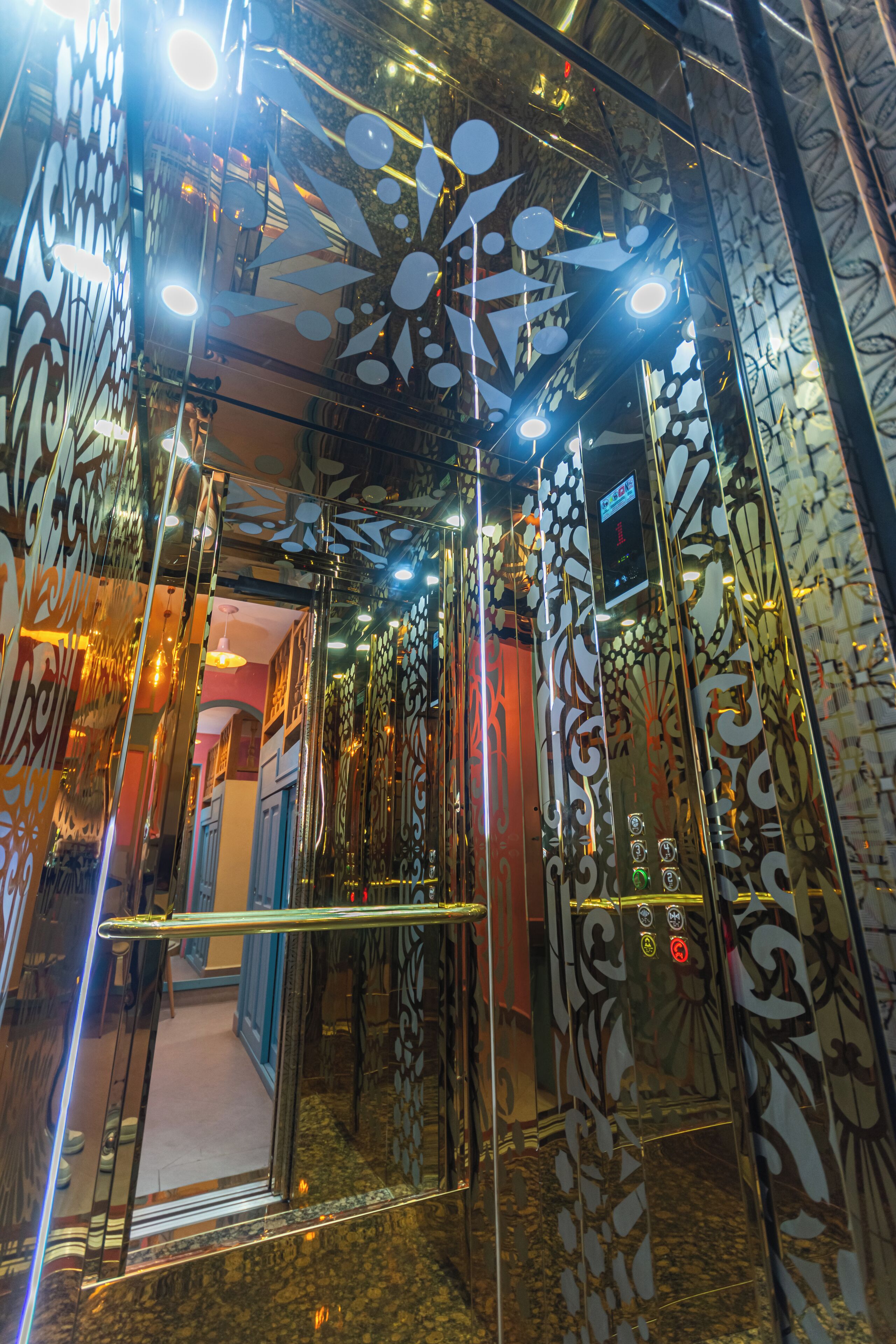 An elevator with ornate, reflective walls and a mirrored ceiling.