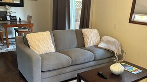 A living room with a gray sofa, a dark wooden coffee table, and a white vase.