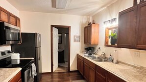 A kitchen with wooden cabinets, a black refrigerator, a microwave, a stove, and a sink.