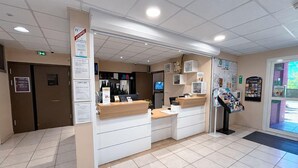 Un espace d’accueil comprenant un comptoir, un réfrigérateur et un tableau d’affichage.