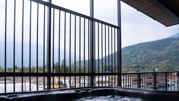 Un bain à remous offrant une vue sur un paysage montagneux, encadré par une rambarde en métal.
