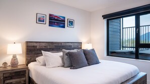 Une chambre à coucher avec un grand lit, deux lampes de chevet, une tête de lit en bois et deux tableaux encadrés accrochés au mur.