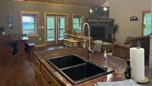 Una cocina amplia con una isla grande, una chimenea y un comedor con una mesa y sillas de madera.