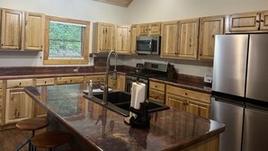 Una cocina moderna con armarios de madera, electrodomésticos de acero inoxidable y una isla grande con taburetes.