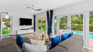 A modern living room with a large flat-screen TV, a ceiling fan, and a glass coffee table. - Fort Lauderdale~River Access~Kayaks~Heated Pool (Fort Lauderdale)